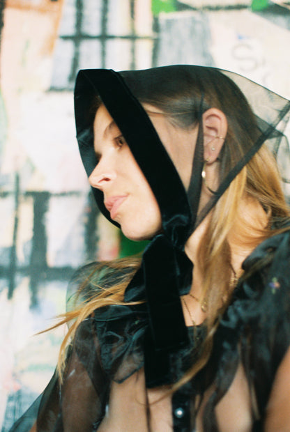 Woman wearing a black hooded garment with a blurred background