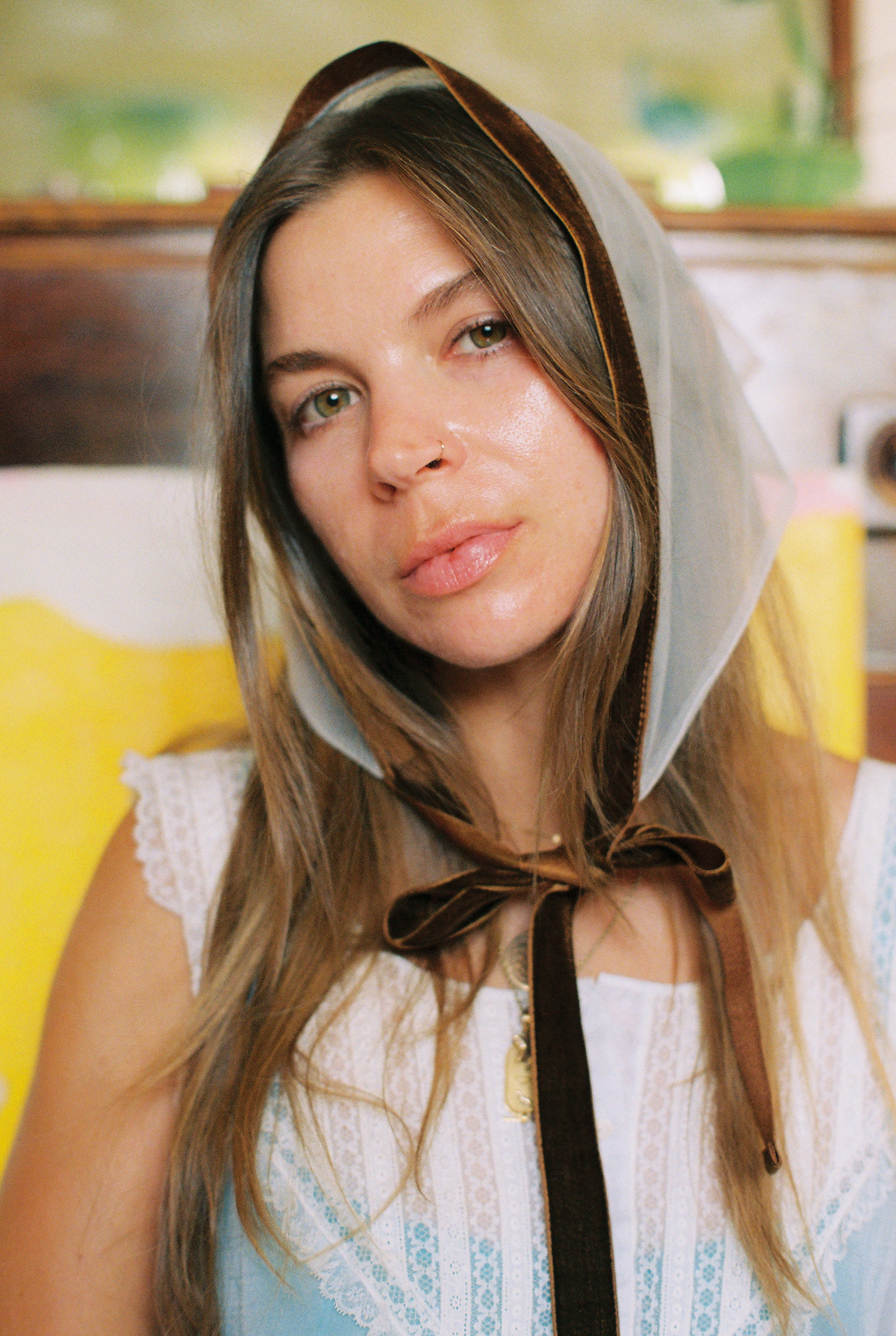 Woman wearing a white bonnet with a brown ribbon in a blurred indoor setting