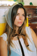 Woman wearing a headscarf with a brown ribbon in a casual setting