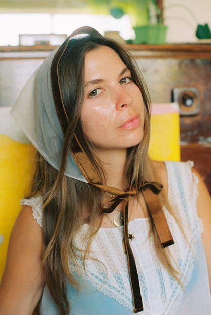 Woman wearing a headscarf with a vintage suitcase in the background