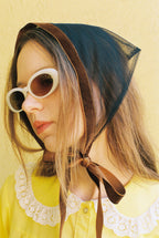 Person wearing a bonnet and sunglasses with a yellow background