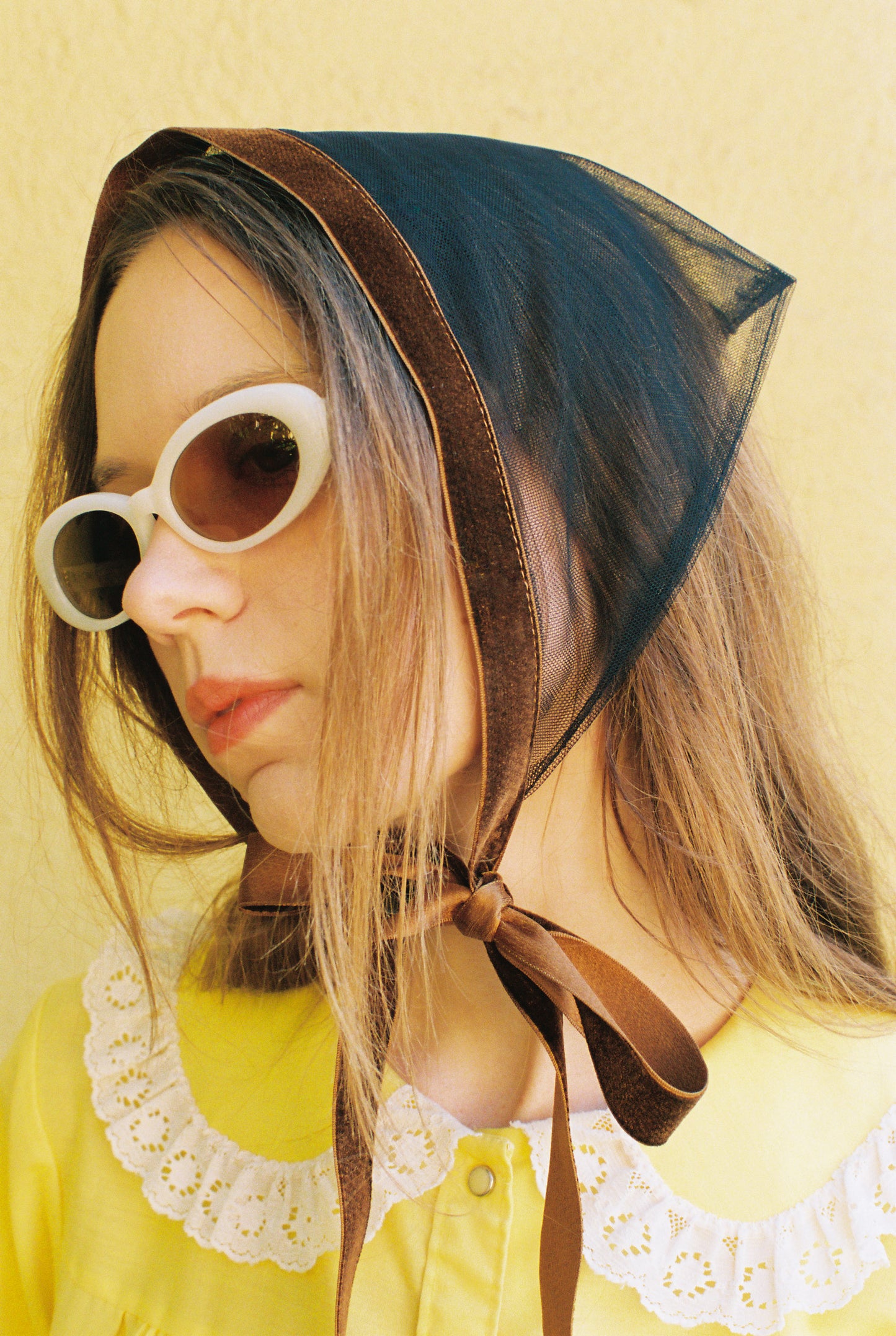 Person wearing a bonnet and sunglasses with a yellow background