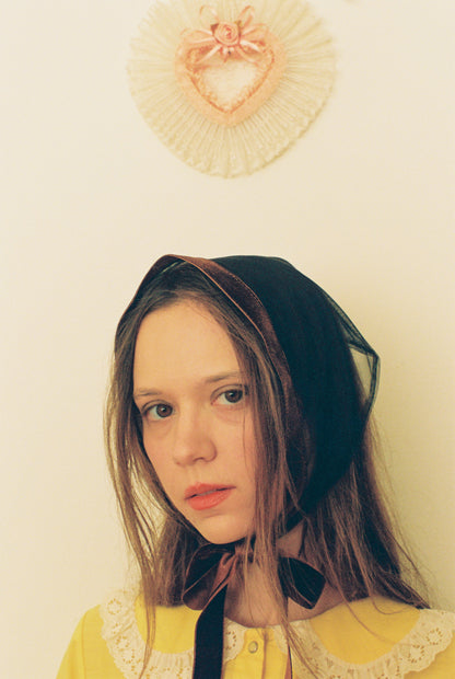 Woman wearing a headscarf with a decorative heart-shaped object in the background