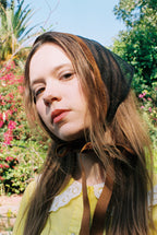 Woman wearing a black headscarf with a blurred natural background