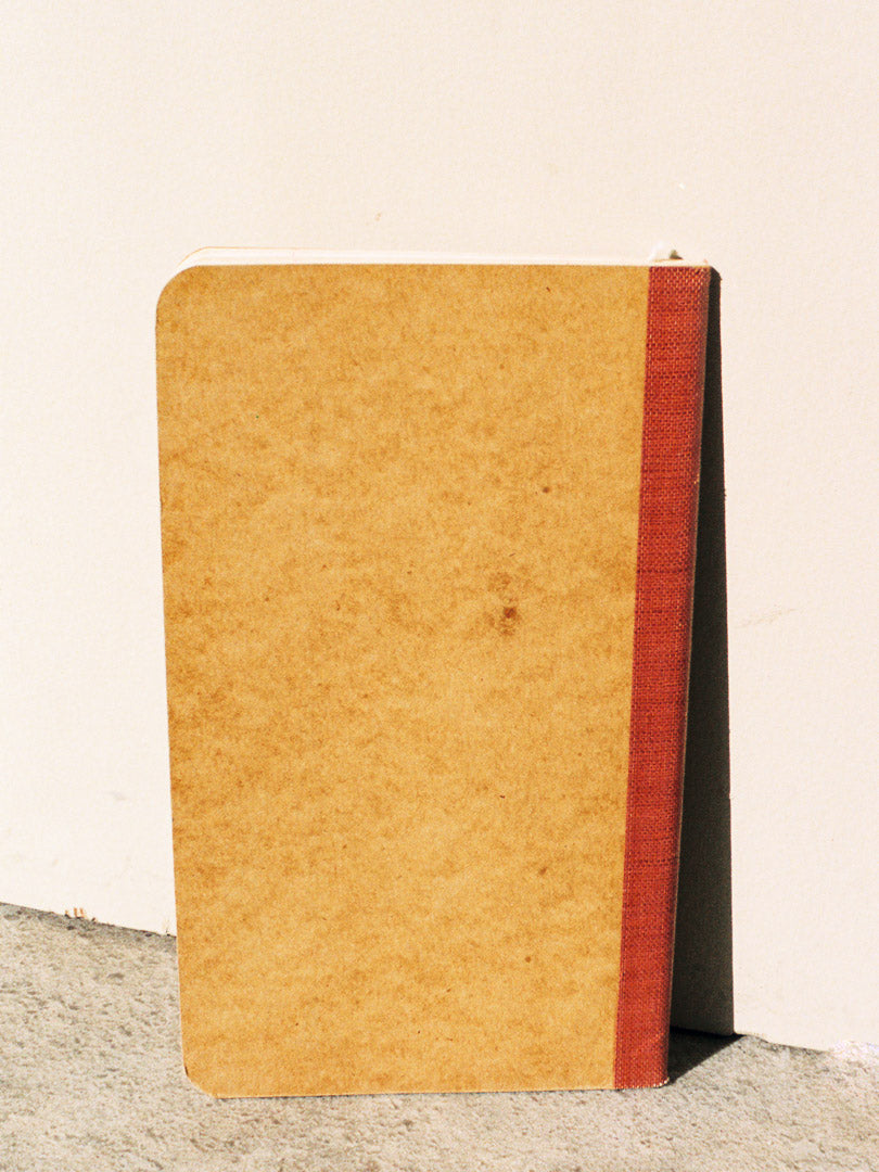 Brown notebook with red binding on a light beige background