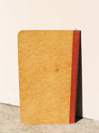 Brown notebook with red binding on a light beige background