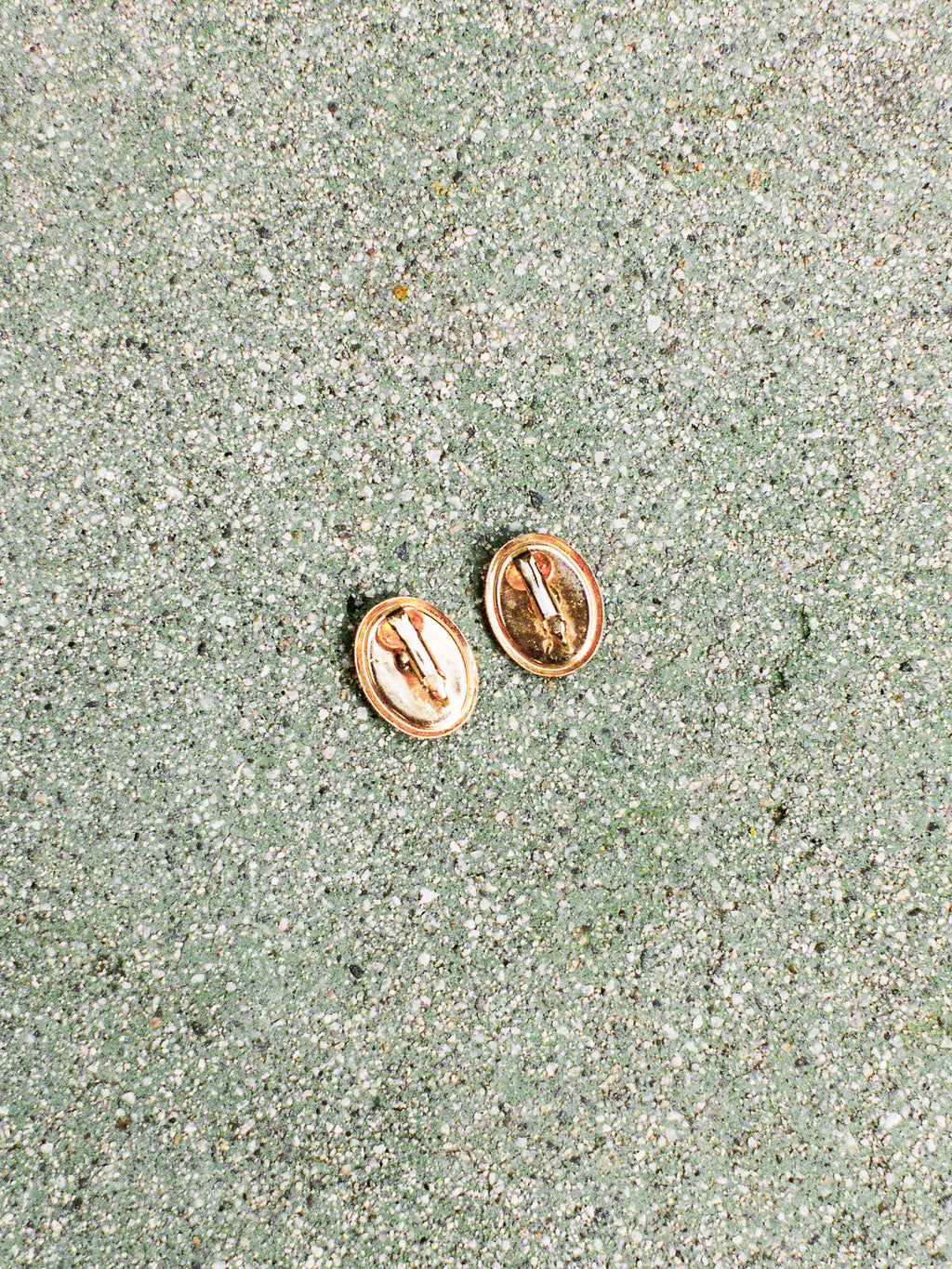 Rose gold earrings on a textured green surface