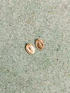 Rose gold earrings on a textured green surface