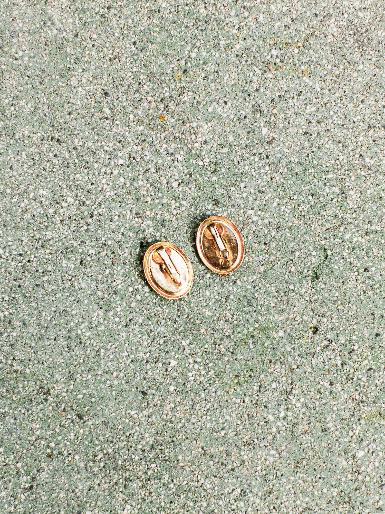 Rose gold earrings on a textured green surface