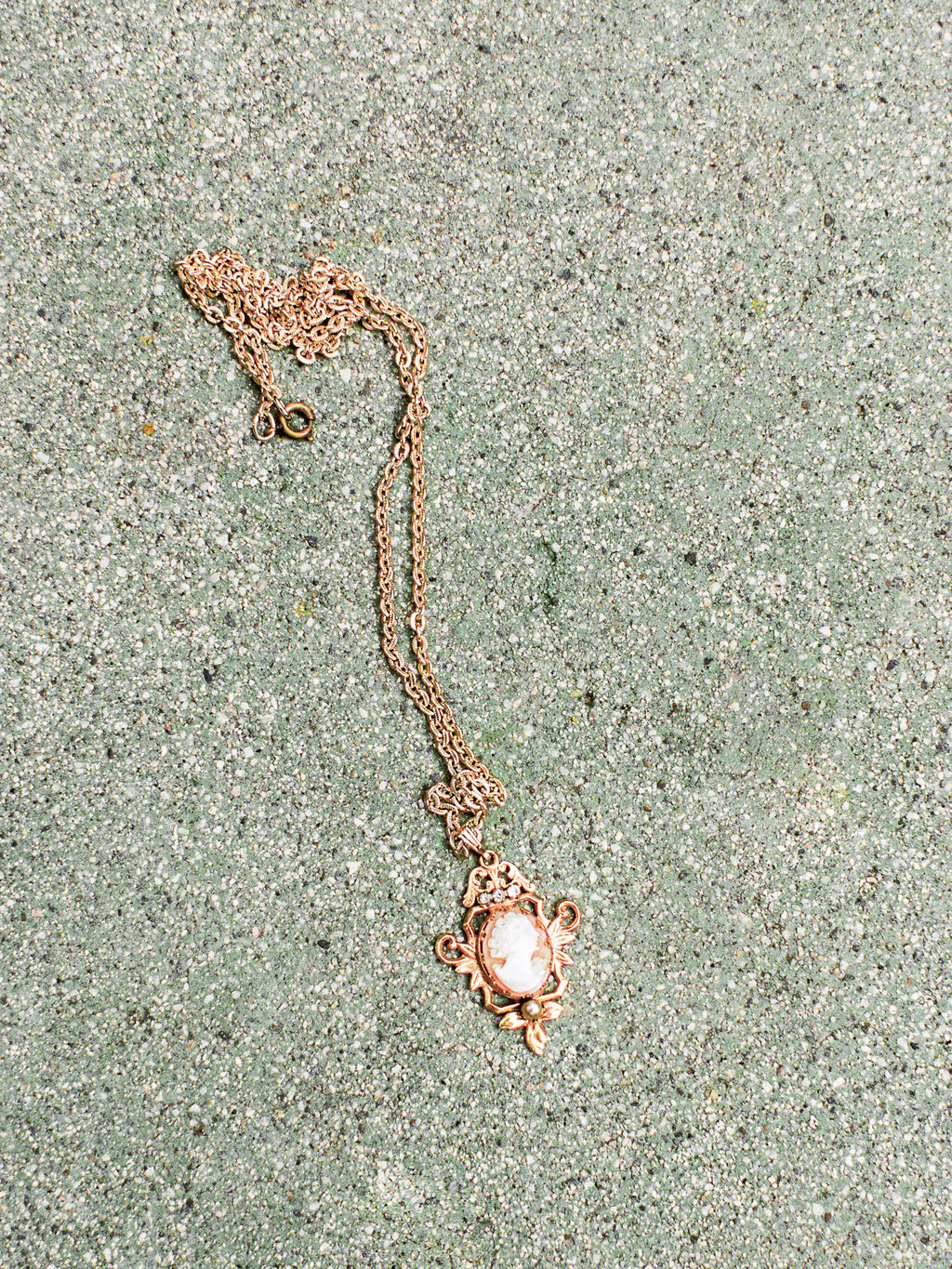 Rose gold necklace with a pendant on a textured surface