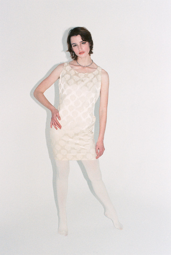 Woman wearing a white textured dress on a plain background
