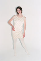 Woman wearing a white textured dress on a plain background