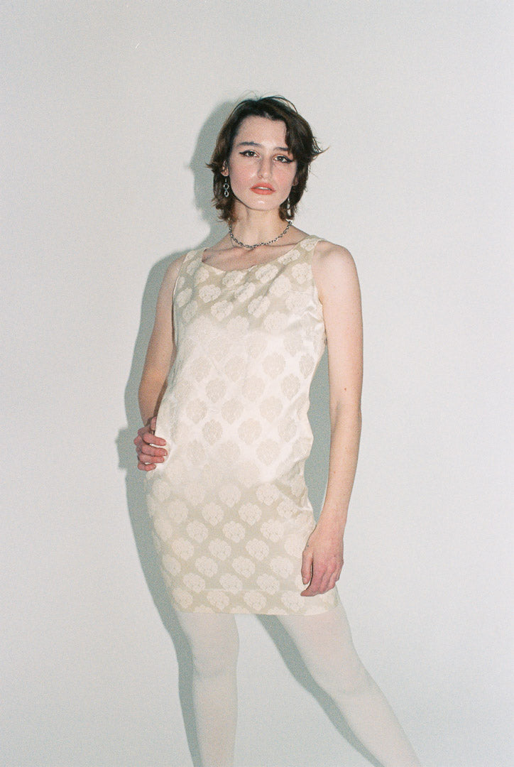 Woman wearing a textured white dress against a plain background