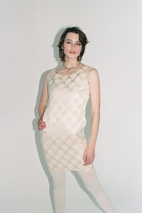 Woman wearing a textured white dress against a plain background